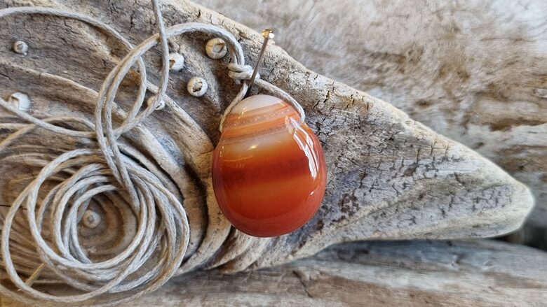 Karneola kulons "Enerģijas pieplūdums" nr 1. Izmērs 2.5 x 2 cm Ar pelēku auklu