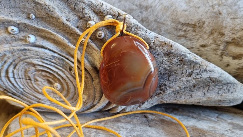 Karneola kulons "Enerģijas pieplūdums" nr 3. Izmērs 3 x 2.5 cm Ar dzeltenu auklu