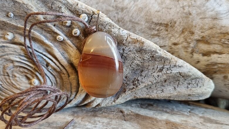 Karneola kulons "Enerģijas pieplūdums" nr 5. Izmērs 3 x 2 cm Ar brūnu auklu