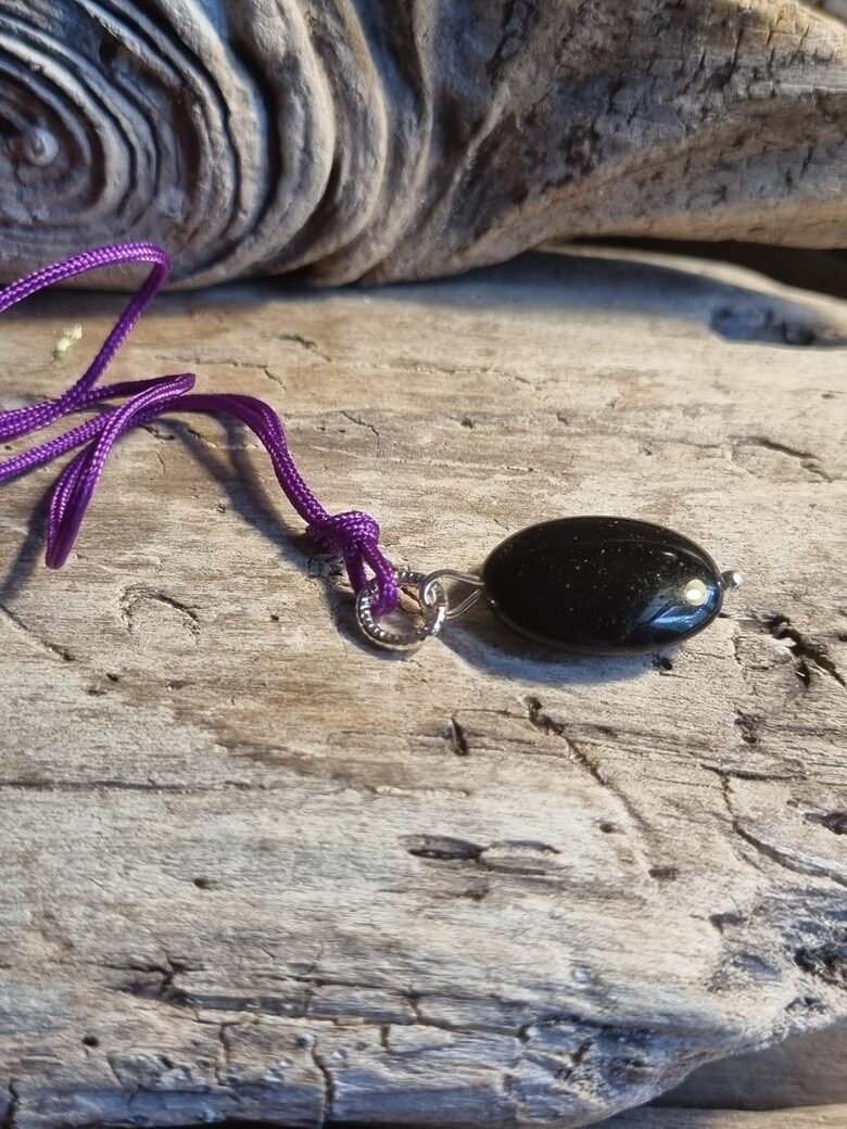 Oniksa kulons "Plakanais" nr 1. Izmērs 2 x 1.3 cm Ar lillā auklu No Brazīlijas