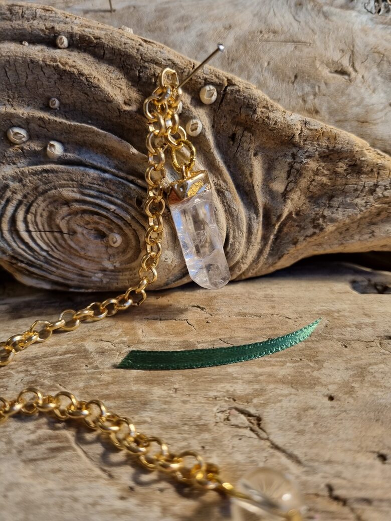 Kalnu kristāla svārstiņš "Enerģijas deva" nr 2. Izmērs 2.5 x 1 cm Zaļa bantīte Ar dabīgiem iespiedumiem