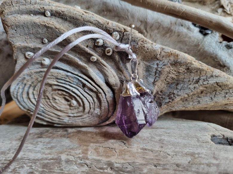 Neapstrādāta ametista kulons ar dubultvirsotni "Pāris" Izmērs 2.5 x 2 cm Ar pelēku auklu No Brazīlijas Ar dabīgiem nobrāzumiem