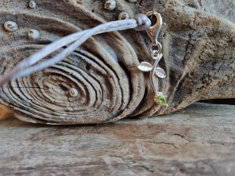 Peridota kulons "Puķīte" nr 2. Izmērs 3 x 1.5 cm Ar pelēku auklu