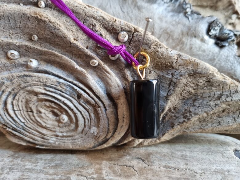 Oniksa kulons "Vienmēr aizsargāts" nr 5. Izmērs 2 x 1 cm Ar lillā auklu No Brazīlijas