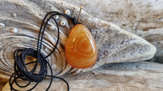 Karneola kulons "Enerģijas pieplūdums" nr 2. Izmērs 3 x 2 cm Ar melnu auklu