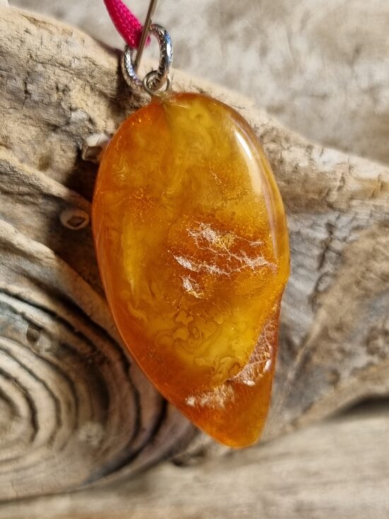 Dzintara kulons "Saulainā lāse" ar sārtu auklu Izmērs 4 x 2 cm 