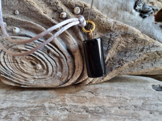 Oniksa kulons "Vienmēr aizsargāts" nr 4. Izmērs 2 x 1 cm Ar pelēku auklu No Brazīlijas