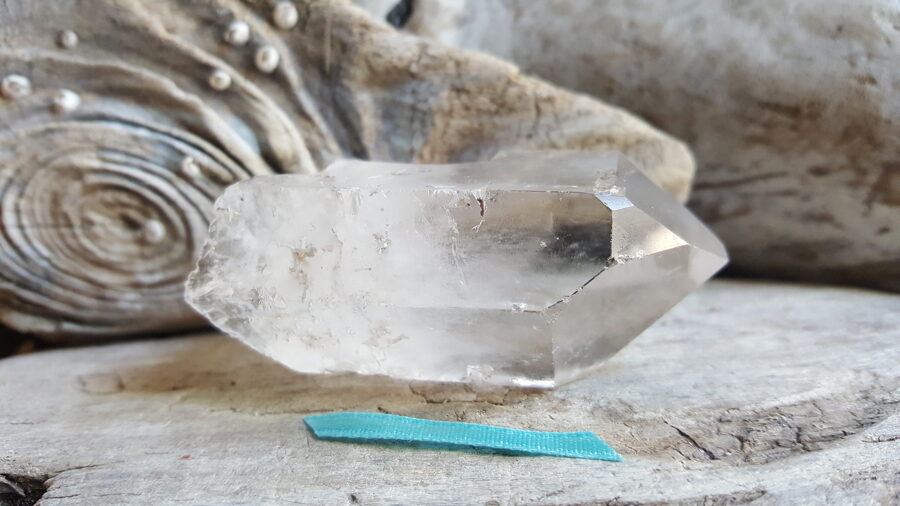 Neapstrādāts kalnu kristāls " Izaugsme" nr 1. Izmērs 6 x 4 x 2.5 cm Zila bantīte Ar dabīgiem nošķēlumiem un iekļāvumiem