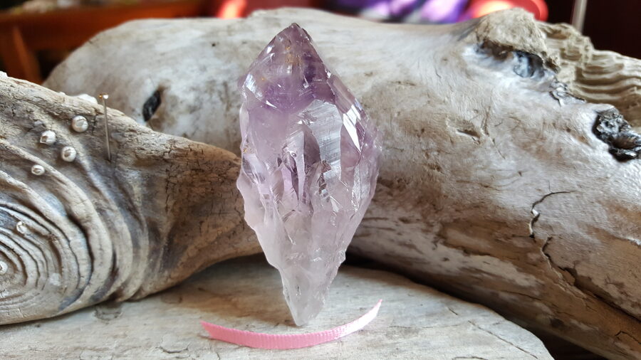 Neapstrādāts ametista kristāls "Atrast ideju" nr 3.  Izmērs 7 x 3.5 cm Rozā bantīte Ar dabīgiem nobrāzumiem
