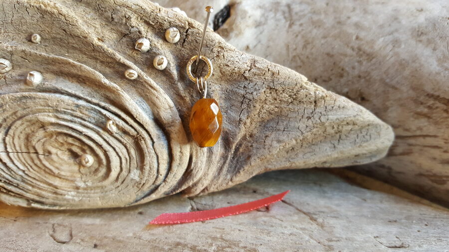 Tīģeracs kulons "Slīpētais" nr 5. Izmērs 1.2 x 0.8 cm Sudraba krāsas metāls Lašu krāsas bantīte