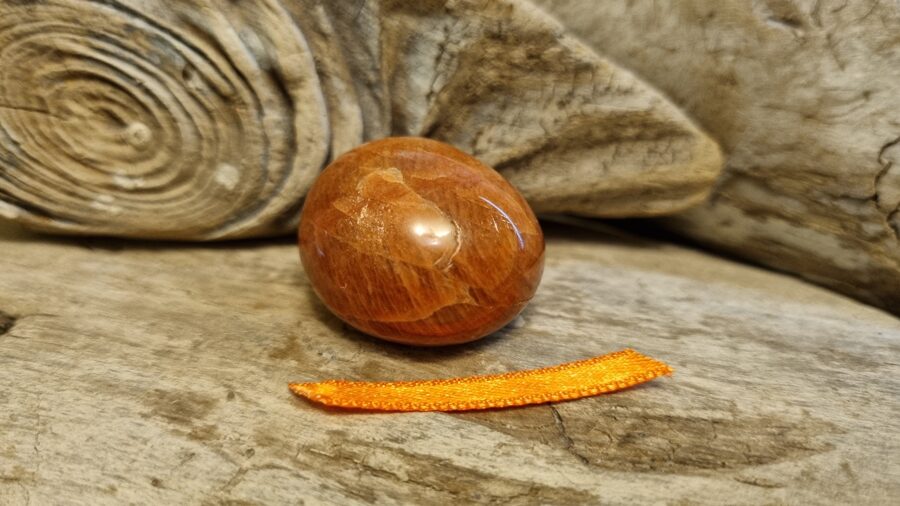 Mēnessakmens "Aprikožu mīlīgais" nr 2. Izmērs 3 x 2.5 cm Oranža bantīte Nomierinošs efekts Madagaskara Ar dabīgiem iespiedumiem