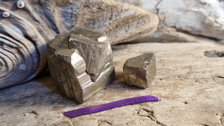 Pirīta kristāli "Liels un mazs" nr 1. Izmērs 2.3 x 2.3 cm un 1 x 1 cm Lillā bantīte Uz darba galda vai mājās uz galda Aizsargās