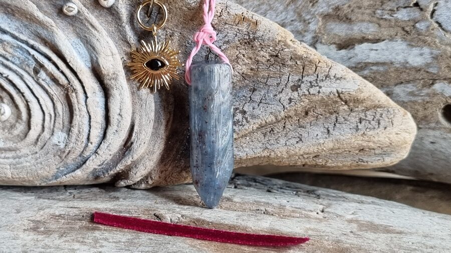 Kianīta kulons ar sauli "Stabilitāte" nr 9. Izmērs 3 x 0.9 cm Ar dabīgām švīkām Bordo bantīte