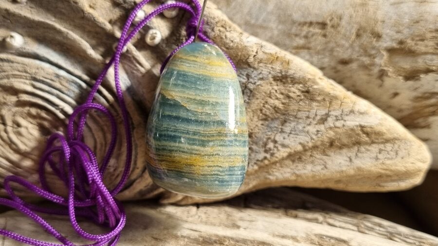 Zila kalcīta/aragonīta kulons "Izteikt sāpi" nr 2. Izmērs 3 x 2 cm Ar lillā auklu No Argentīnas 