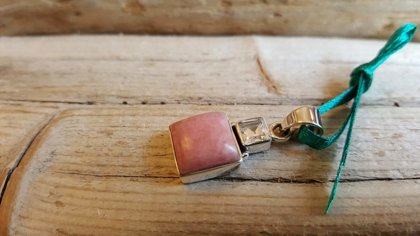 Rodohrozīta kulons ar kalnu kristālu sudrabā. Zaļa bantīte. Izmērs 2 x 1.2 cm.